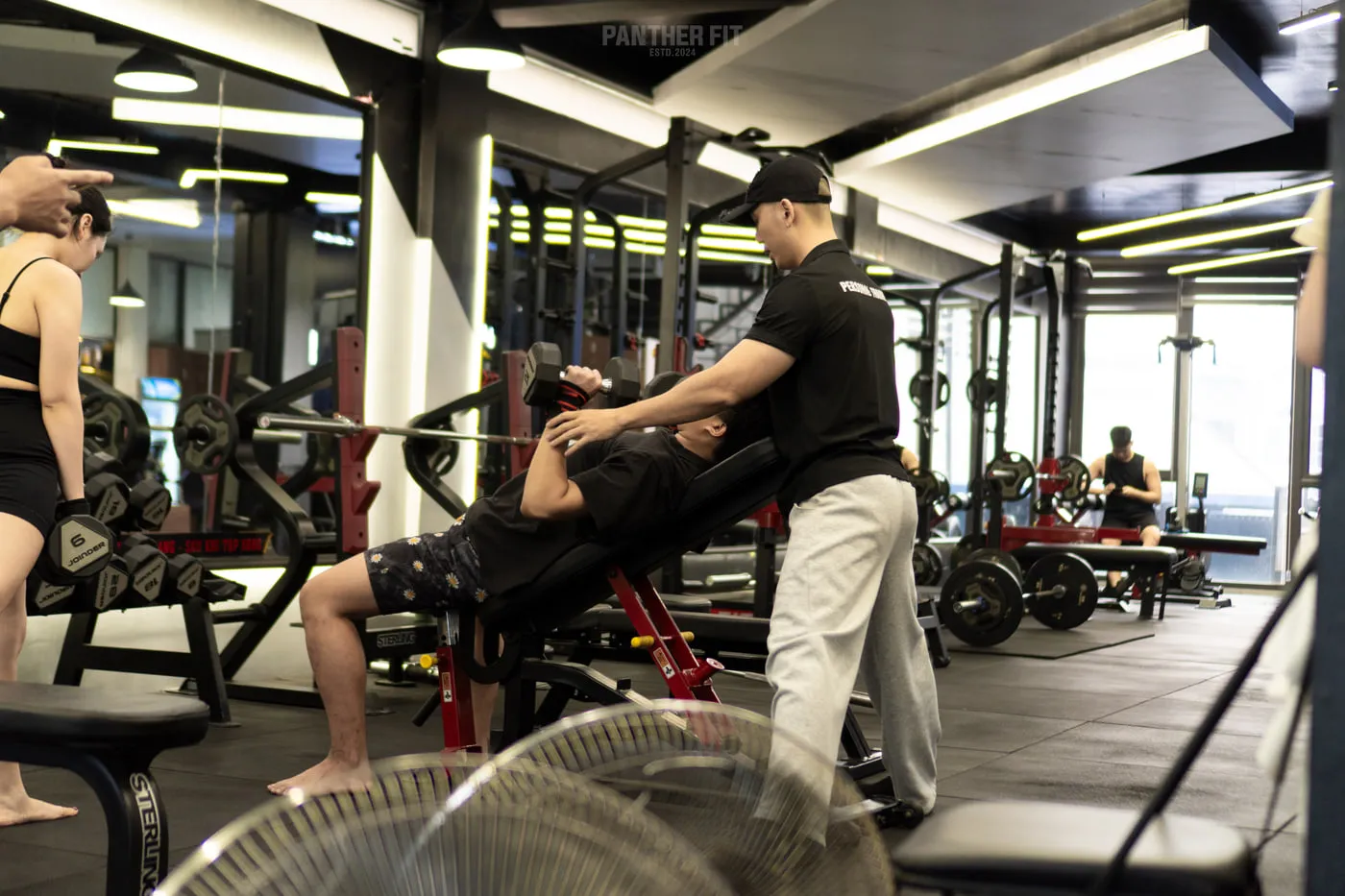 Huấn luyện viên Hà Minh Quyết đang hỗ trợ hội viên tập tạ tay tại Panther Fit